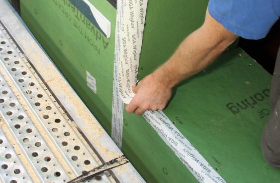 Applying Wigluv tape to the side jamb and lapping down over the sill tape.