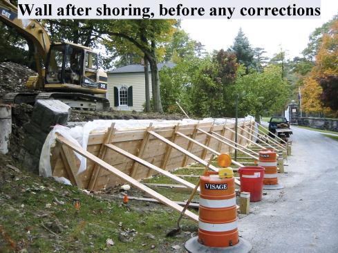 A system of horizontal kickers and diagonal braces bearing against 6x6 posts driven deep into the soil - one of which is visible just to the right of the traffic beacon - held the wall in position during excavation of the poorly drained original backfill.