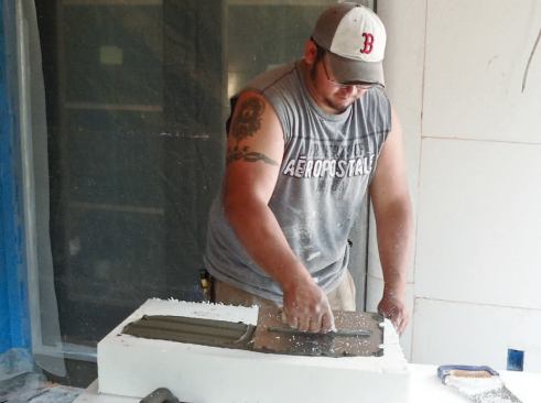 The EPS panels are glued to the walls with adhesive that's been applied with a notched trowel. The notches are vertically oriented so that moisture can drain down the channels between the membrane and the foam and out of the wall assembly wherever the DrainEdge has been installed.
