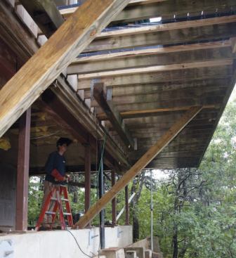 Diagonal 4x6 braces anchored atop the grade beam stiffen the cantilevered deck above.