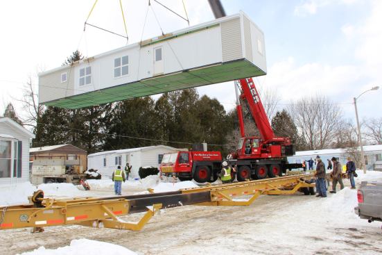 The crane lifts the 70-foot-long unit off its trailer and swings it slowly toward its intended location on the new foundation.