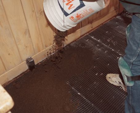 The mix is first dumped around the perimeter of the room to establish screeding points for leveling the general floor area.