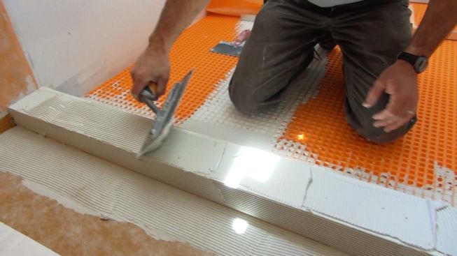 Boucher tools one-eighth-inch grooves into the mortar bed using a special Kerdi trowel. Applying a consistent, uniform, measured amount of mortar to the substrate before installing the membrane is one of the keys to success for the system.