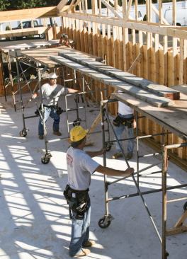 Fall-protection harnesses and industrial scaffolding are not practical when setting roof trusses. For workers assigned to the center of the trusses,the crew sets up rolling pipe staging to move along with the framing operation.