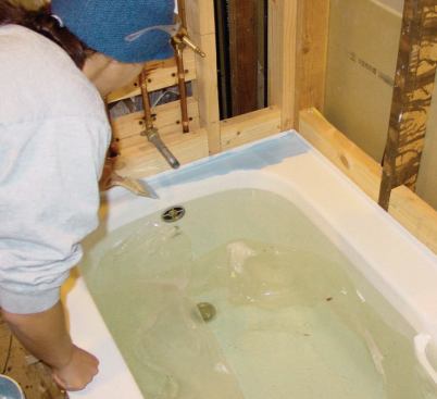 Two coats of Liquid Mask are brushed on to the perimeter of the tub, leaving a rubbery coating that prevents it from being scratched by the plywood cover.