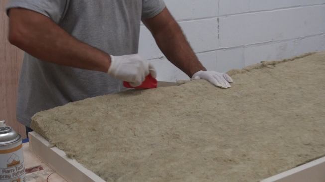 Slicing the sound-absorbing insulation to fit with a knife.