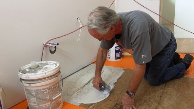 Boucher works a slurry of latex-modified mortar into the Advantech subfloor, to ensure a good bond between the mortar and the wood structural panel.