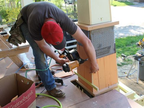 Fenton staples on another course of shingles as he works up the column.