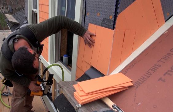 Pollard sets the first full course of shingles above the roof line, leaving a one-inch gap above the heavy-duty metal flashing.