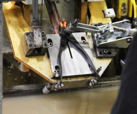 These pliers have been assembled and are undergoing selective hardening of the cutting edges. The edges are heated by induction—a non-contact method of electro-magnetic heating. When the edges reach a specified temperature they are quenched by dropping the tool into the liquid below. This leaves the edges harder than the rest of the tool. A similar operation is performed on the jaw faces of gripping tools such as pliers (
click here for video).