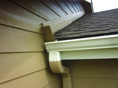 A true kick-out flashing, like this one, gathers water and directs it into the gutter. Note also the wide gap above the tim board follwing the rake. This allows any water flowing down the roof to be directed by the step flashing to the gutter, instead of wicking into the sidewall siding boards.