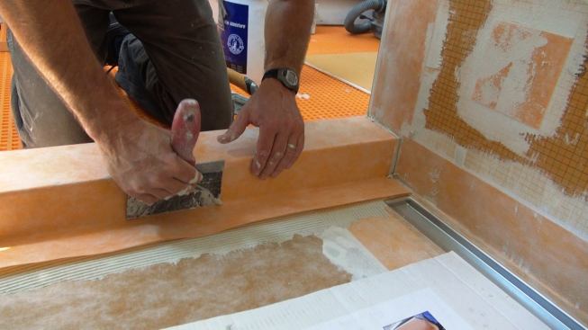 Boucher works the membrane into solid contact with the mortar using his six-inch spackle knife.