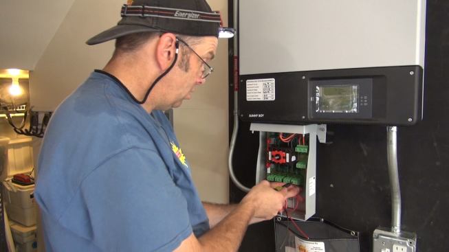 Electrician Ted Houghton connects conductors to terminals in the direct current disconnect switch serving the system’s inverter.