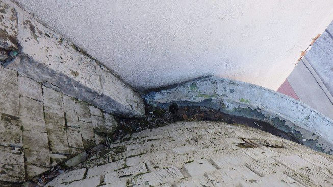 A brick ledge at the intersection of the roof plane and the adjacent building had been a difficult place to flash well and, where it died into the gutter at the base of one turret, it created a trap for leaves and other debris that impeded drainage.