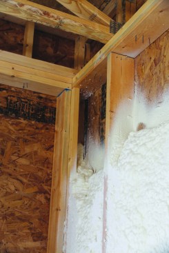 The garage-wall cavities are insulated with an open-cell spray foam. If installed to a depth of at least 4 inches, an open-cell foam provides a decent air seal to close off small cracks and gaps in the stud bays. Notice that the author frames with a California corner, so wall corners can be filled with insulation.