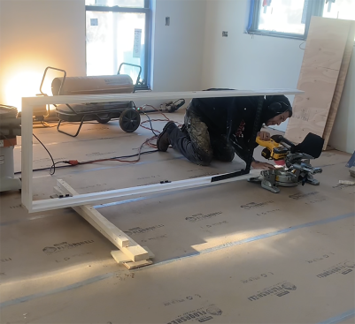 You may need to cut the jamb down in length befoe standing the unit in the rough opening  for scribing. The author makeshis  jamb cuts using a miter saw on the floor. Without the door, the jamb legs will flop around, so he may attach a temporary stretcher 12 inches up from the bottom of the unit. In the photo above, he uses a framing square as my stretcher—a fast solution that works for a 2'-0" door.