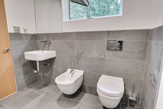 The author replaced the existing fixtures with wall-hung models, which don’t protrude as far into the room as floor models, so there’s more usable floor space. Being raised off the floor makes them easy to clean around, too. Height above the floor can be chosen during installation; the author opted to install the bidet and toilet at an ADA-compliant height of 19 inches.