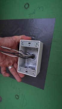 By using a surface-mounted metal box so only the wire, not the entire box, needed to be sealed.