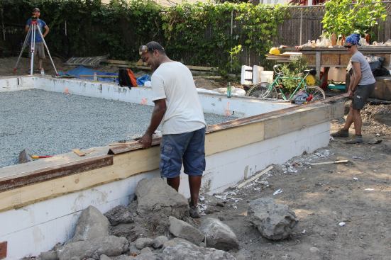 Scotland Willis and Placetailor project manager Laura Doyle set pieces of angle iron down onto the boards screwed to the ICFs, to serve as a hard straight-edge guide for the concrete screed that will be used to strike a level surface on the building’s first-floor concrete slab.