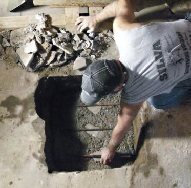 I position the first three pieces of rebar, setting them on top of concrete fragments, which helps them stay in place. I lay two more pieces of rebar in the opposite direction, and continue adding concrete until the hole is filled.