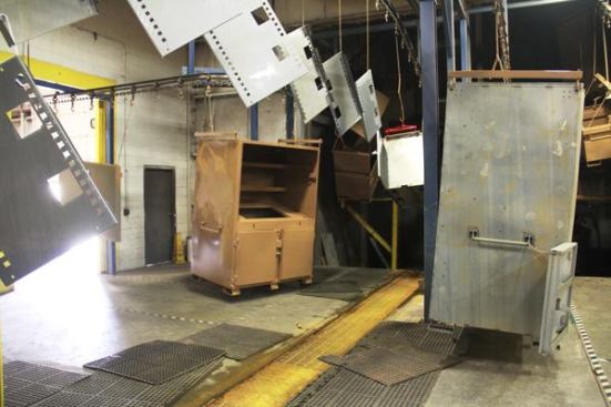 This area is like Grand Central Station, with boxes and parts being conveyed every which way. Just washed items are sent to the lower level to be dried by heated air. Dry pieces come up and are sent to the powder coating area. Freshly powder coated items are conveyed to an upper level where the finish is baked on. And finished boxes come down from above and are sent to the final assembly area.