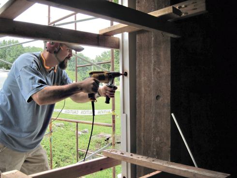 To attach a new wood window frame to the stone with threaded rod, the author first drilled a hole large enough to accommodate the washer and nut, using a wood countersink.