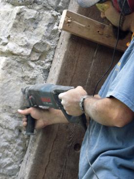 To avoid ruining the bit, the author continued drilling through the wood with a 1/2-inch masonry bit until he hit the stone. Then, with the frame out of the way, he continued drilling with a 5/8-inch masonry bit, making a hole large enough for the 1/2-inch rod and the epoxy.