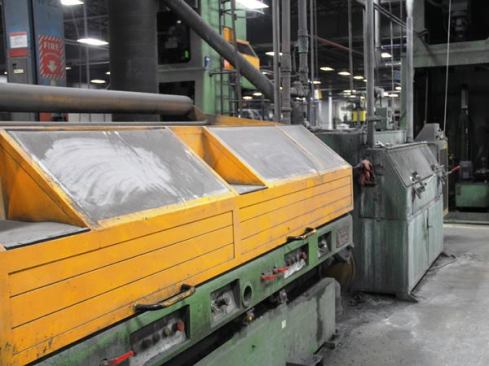 The now clean wire is pulled into a wire drawing machine. You’re looking at the back half of one of many such machines in the factory. The hinged yellow cover can be lifted out of the way to access the drums and dies that are used to bring the wire to the correct diameter for the fasteners being made.