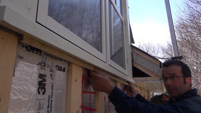 Pollard places a thin spacer under the soffit and window trim, padding out the wall to allow an exhaust point for air movement in the cavity behind the siding and trim in the rain screen assembly.
