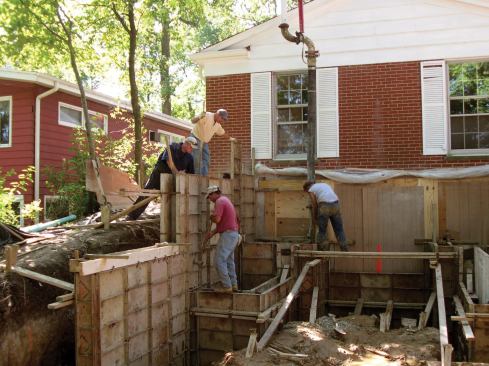 Access was limited, so the crew used a bucket on a skid-steer loader to place the concrete for the footings; the walls were pumped.