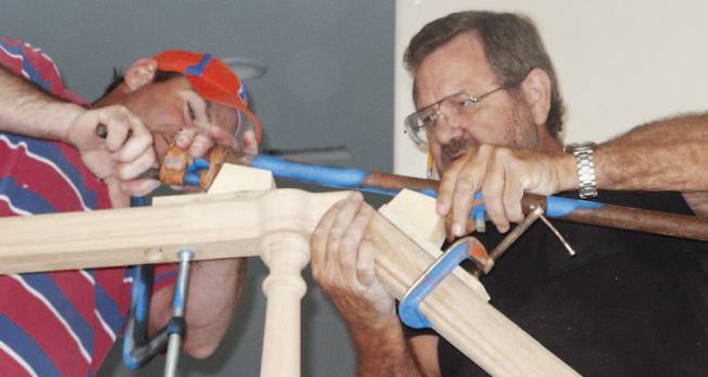 A pair of angled blocks attached to short pieces of plywood create leverage points for the pipe clamp used to draw the joint together.
