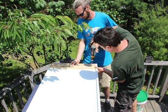 Joe and Jeff use the upper cleat as a guide, aligning it to the panel’s upper edge, and fastening the lower cleat to the panel itself. The upper cleat and two additional cleats will be attached to the cabinet, providing a way to fasten the cabinet to the end panel.