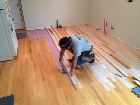 Continue installing boards across the floor as you would for new construction until you meet the existing floor on the other side. Manny was able to reuse flooring that he'd taken out earlier. The key is making sure the edges are clean and that the tongues and grooves are not damaged.