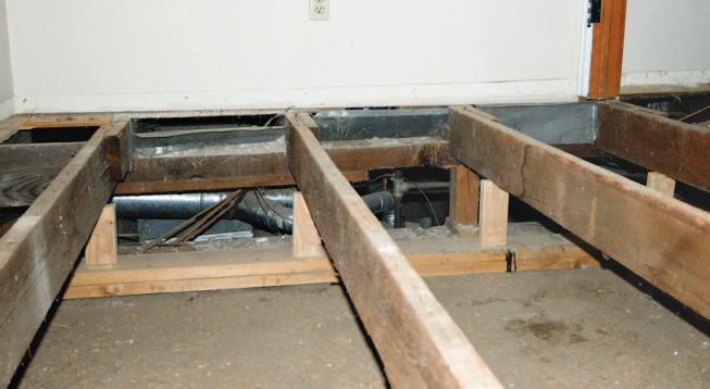 At the center girder, however, the crew had to provide shoring with short blocks set on plates so that the first-story bearing wall would be supported as the joists were cut away.