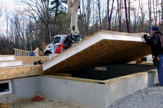 Finally, the crane lowers the panel into place, where it will be nailed to the sill.