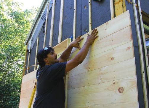 Luke Small applies a rainscreen siding detail over the insulation jacket.