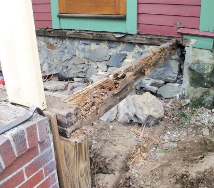Rotted girders in the old framing extended just an inch into poorly hewn pockets in the rough stone foundation. The author repointed and parged the existing pockets and cut additional ones for new double 2x10 beams.