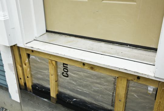 Exterior extensions to the jambs and threshold rely on composite lumber and caulk.