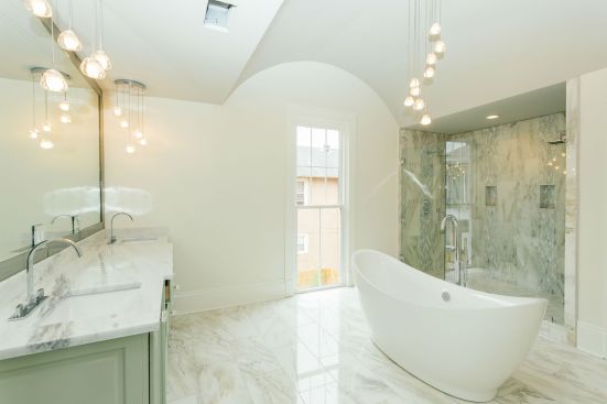 One of the 3 full bathrooms in the home, the suite features a vaulted ceiling and standalone tub for an historic feel, while the open plan and light colors provide a modern aesthetic. 