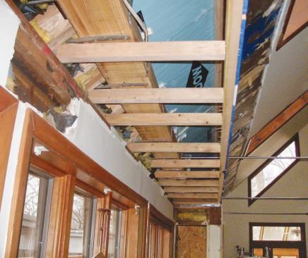 A new soffit hides the horizontal glulam beam where it runs through the cathedral bump-out; the tie rods were later hidden in false pine beams.