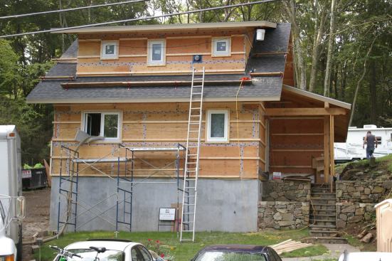 Plywood sheathing joints were taped before horizontal 2x3s and 1/2-inch plywood strips were added. HRV exhaust is seen between dormer windows.
