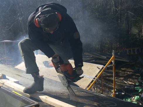 Chris Corson saws the eaves off his house on a freezing-cold morning in Belfast, Maine before wrapping the entire building in Grace Ice and Water Shield and polyiso insulation.