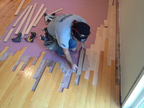 To blend the new boards in with the old, Manny starts with a length that will give him an acceptable staggered seam. Then he inserts the board at a slight angle to engage the tongue and groove properly.