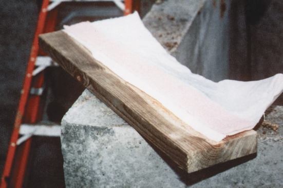 Before installing the mudsill, a 6-inch-wide strip of poly is embedded in Tremco sealant and stapled to the underside. A 2 3/4-inch-wide strip of foam sill seal is stapled over the poly, and then the sill is flipped over and bolted in place. The poly flap faces the exterior.