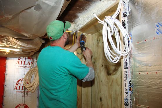 Shane Fenton spot seals a joint in the basement door jamb.