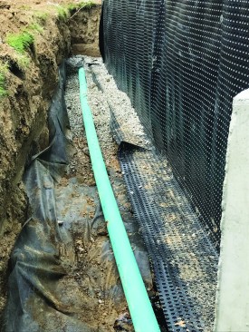 When laying down perimeter drains, the author first lays down filter fabric, then embeds the pipe in gravel. Large (1-inch) gravel creates plenty of voids through which water can freely move, but the filter fabric needs to be there so soil won’t fill up the voids over time.