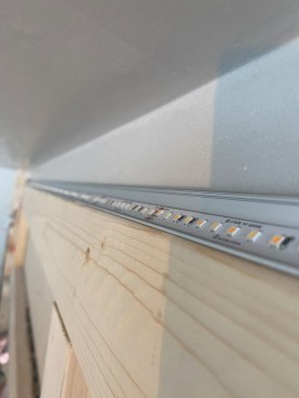 The strip lighting clips to the track with the emitters projecting upward at an angle.