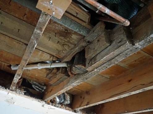 Plumbers over the century had done a good job of carving up floor joists.