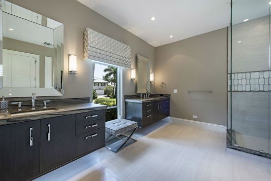 In the newly expanded master bath, dark oak cabinetry and chrome continue the design theme found downstairs while a tub is replaced with a sleek walk-in shower.