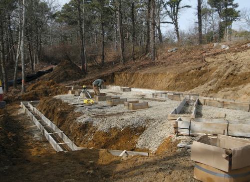 To improve traction for workers, the authors spread stone over the wet clay soil. Footing forms were placed on top of the stone.